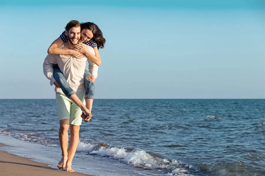 Lachendes Pärchen am Strand verbringt romantische Momente bei gemeinsamen Urlaub in Ahrenshoop.