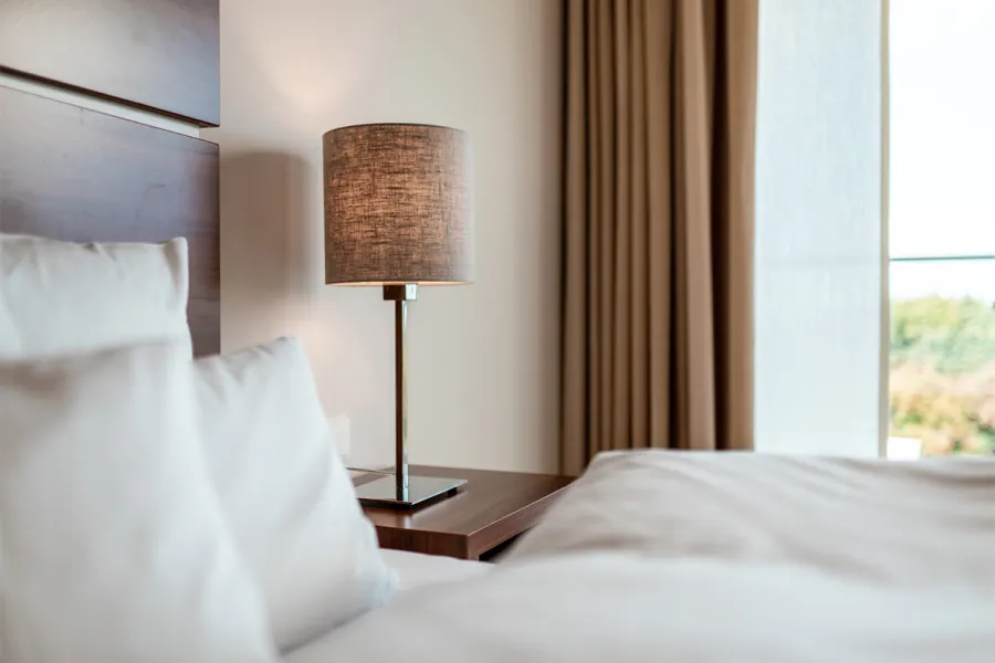 Gemütliches Bett mit moderner Einrichtung im Zimmer im THE GRAND Ahrenshoop an der Ostsee.