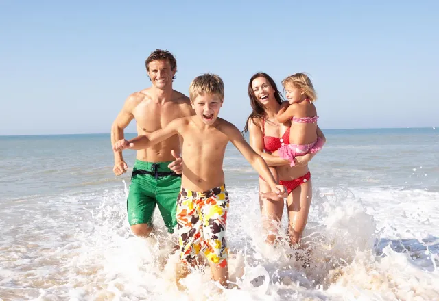 Eine Familie hält ihr Kind an den Händen und spielt am Ostsee Strand © Adobe Stock, Monkey Business