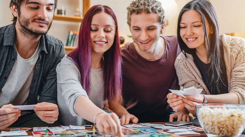 Vier Freunde spielen ein Strategiespiel und lächeln.