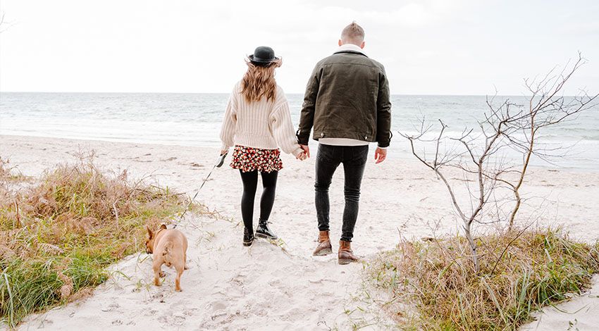 Ein Pärchen mit Hund an der Leine spaziert entlang der Ostsee in Ahrenshoop.