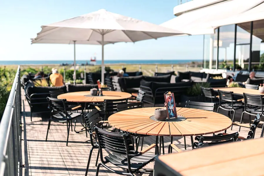 Frühstücksterrasse mit gedeckten Tischen, Sonnenschirmen und Sitzplätzen im Freien nahe der Ostsee.
