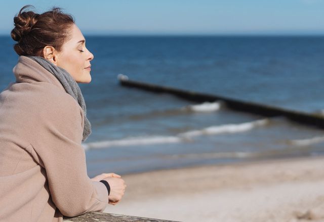 Frau geniesst frische Seeluft und Sonnenlicht an der Ostsee.