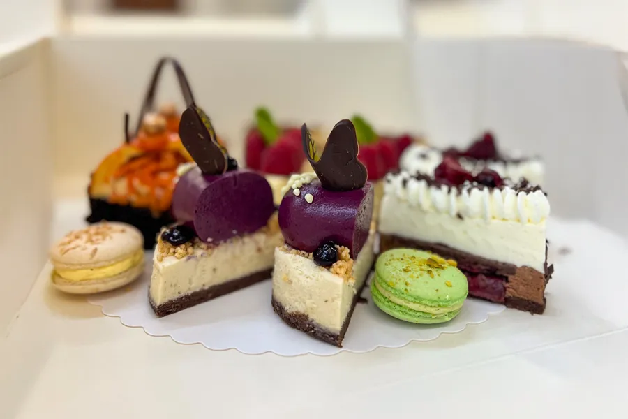 Auswahl an Törtchen und Macarons in einer Kuchenbox aus der THE GRAND Patisserie.