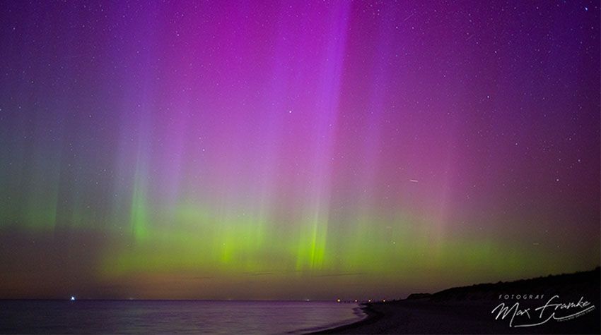 Polarlichter in Violett und Grün über der Ostsee bei Nacht, fotografiert vom Strand aus.