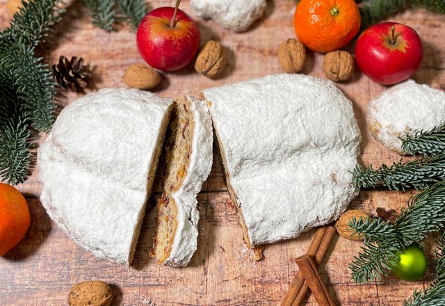 Ein aufgeschnittener Stollen liegt auf einem weihnachtlich dekorierten Tisch.