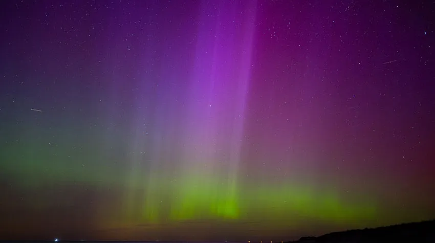 Farbenfrohe Polarichter in Violett und Grün am sternenklaren Himmel über der Ostsee in Ahrenshoop.