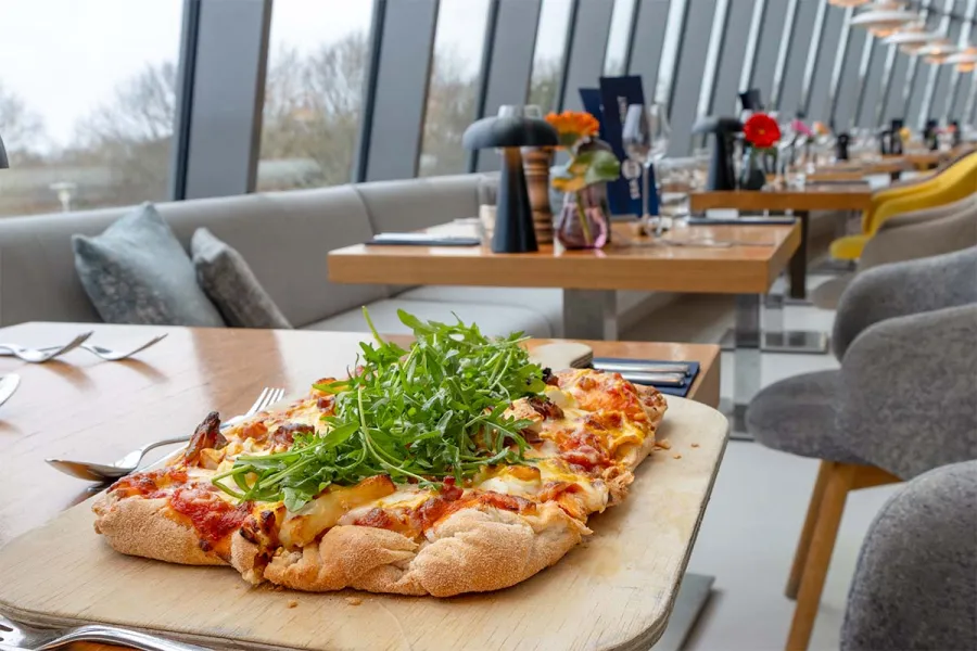 Pizza auf Holzbrett mit frischen Zutaten im Restaurant SEASIDE im THE GRAND Ahrenshoop