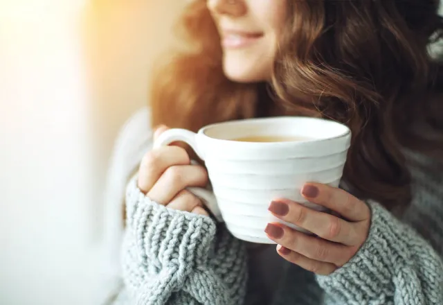 Eine junge Frau mit einer Tasse Tee in der Hand.