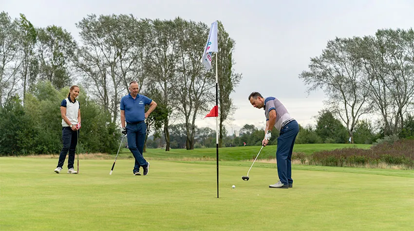 Drei Personen stehen kurz vor dem Ziel auf dem Golfplatz von Warnemünde.