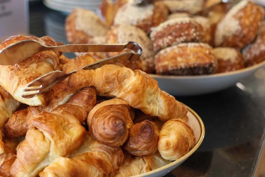 Frische Croissants und Brötchen liegen angerichtet in Schalen auf einem Frühstücksbuffet an der Ostsee.