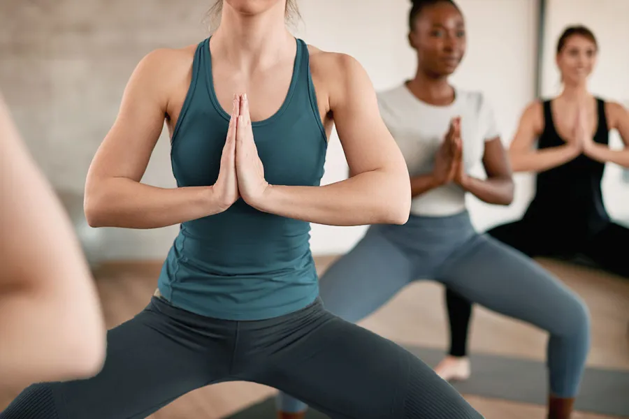 Drei Frauen praktizieren Yoga auf Fischland-Darß in einer kraftvollen Standhaltung.
