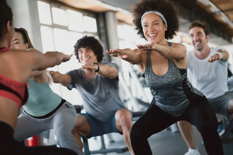 Gruppe trainiert gemeinsam Kniebeugen im Fitnessstudio des THE GRAND Ahrenshoop