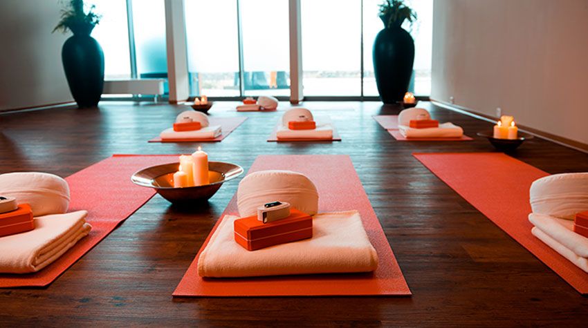 In einem Yogaraum des THE GRAND Ahrenshoop liegen Matten mit Kissen, Decken und Kerzen bereit.