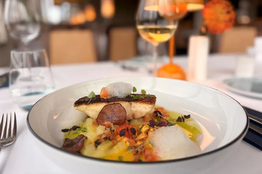 Gebratenes Fischgericht mit Gemüse und Schaum wird im THE GRAND Ahrenshoop serviert.