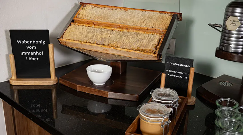 Eine frische Honigwabe im Frühstücksbereich des THE GRAND Ahrenshoop. Daneben hausgemachte Erdnussbutter und Schokocreme. ©Max Framke