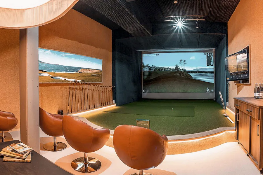 Moderner Golfsimulator mit Leinwand, Kunstrasen und Ledersesseln an der Ostsee.
