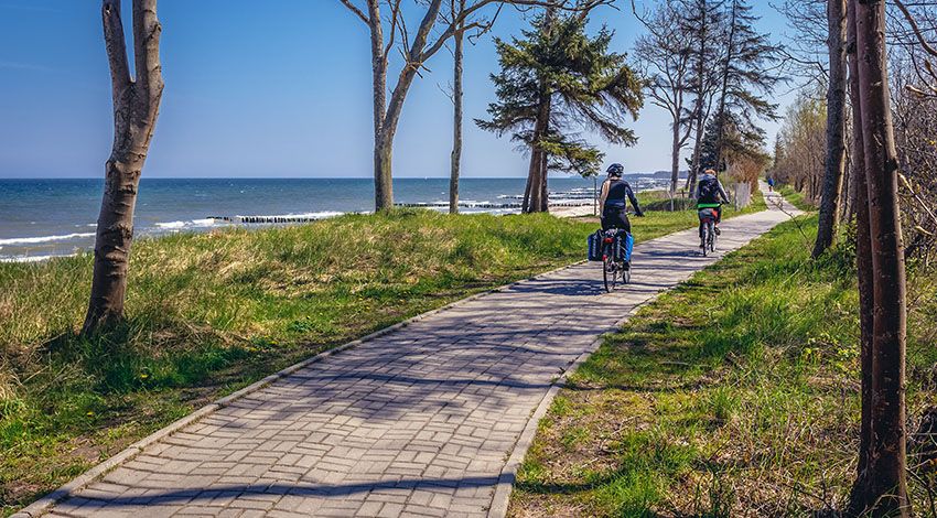 Radweg an der Ostsee mit zwei Radfahrern bei sonnigem Wetter.