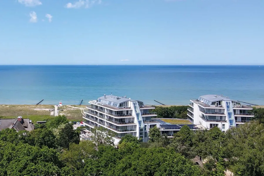 Luftaufnahme vom Hotel THE GRAND Ahrenshoop zwischen Dünen an der sommerlichen Ostsee.