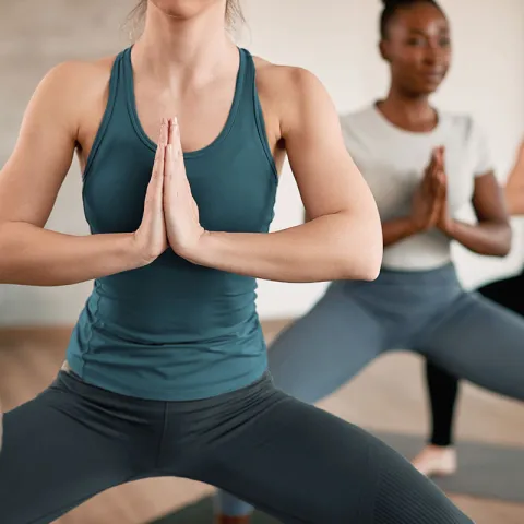 Drei Frauen praktizieren Yoga auf Fischland-Darß in einer kraftvollen Standhaltung.