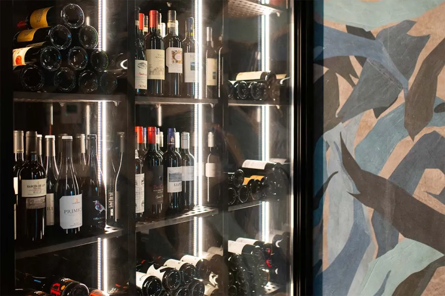 Beleuchteter Weinschrank mit verschiedenen Weinflaschen im Restaurant WEITBLICK in Ahrenshoop.