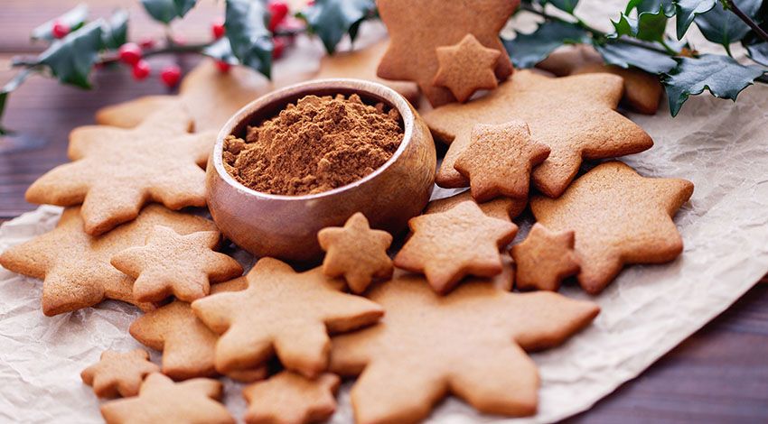Lebkuchen, umgeben von verschiedenen Gewürzen, dekorativ arrangiert.