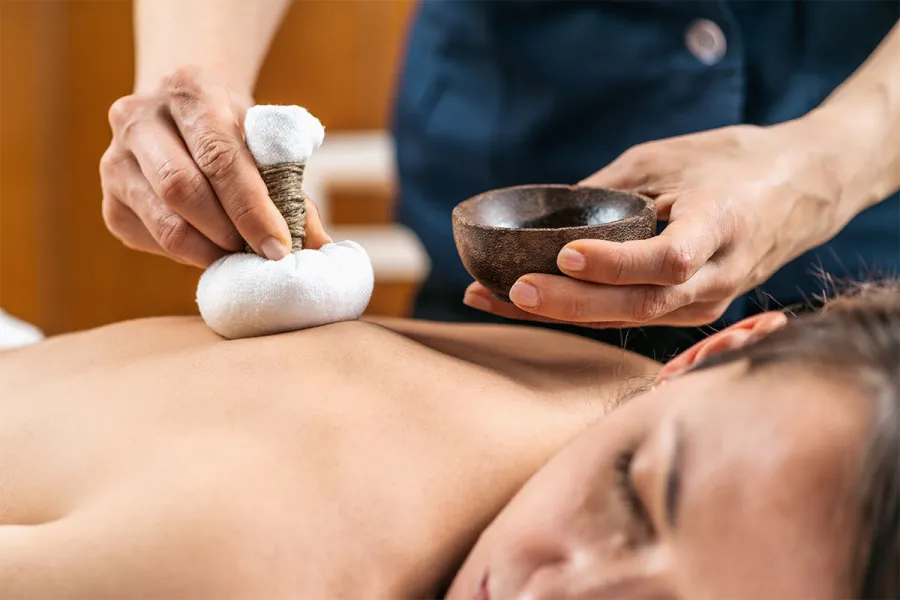 Frau erhält eine Kräuterstempel-Massage im Spa-Bereich an der Ostsee.