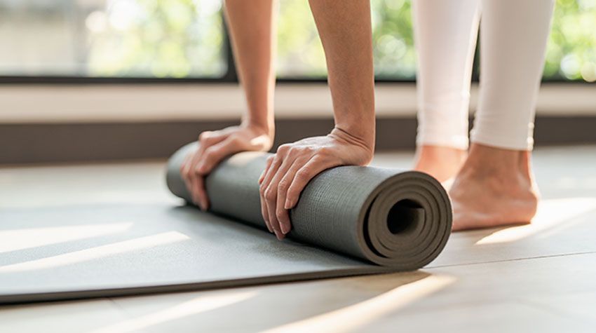 Eine Person rollt eine Yogamatte aus.