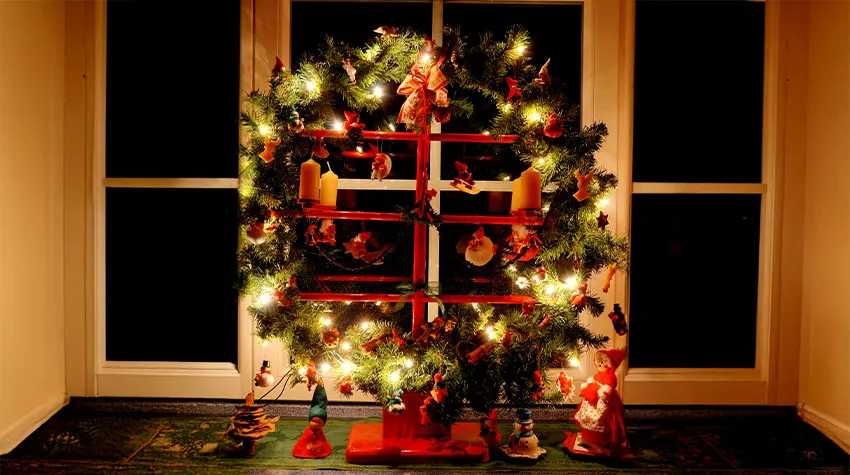 Traditionell geschmückter Jöölboom auf einer Fensterbank, beleuchtet.