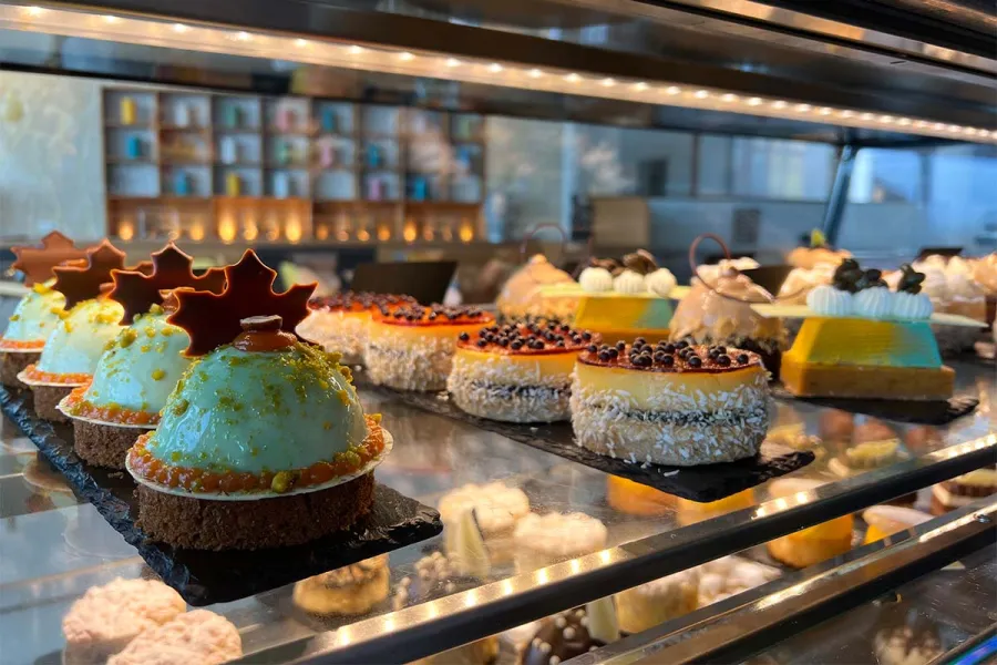 Verschiedene dekorierte Törtchen stehen in der Vitrine der Patisserie im THE GRAND Ahrenshoop.