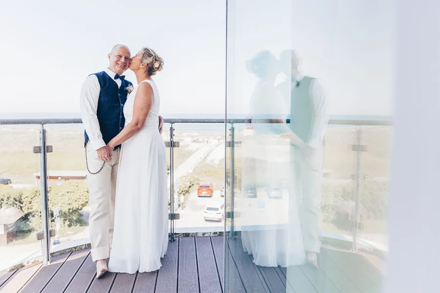 Brautpaar steht auf einer Terrasse mit Blick auf die Ostsee im THE GRAND Ahrenshoop.