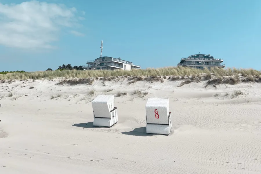 Zwei Strandkörbe am Ostseestrand vor den Dünen mit Blick auf THE GRAND Ahrenshoop.