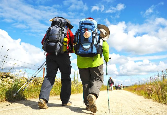 Zwei Personen mit Rucksäcken wandern einen Weg entlang.