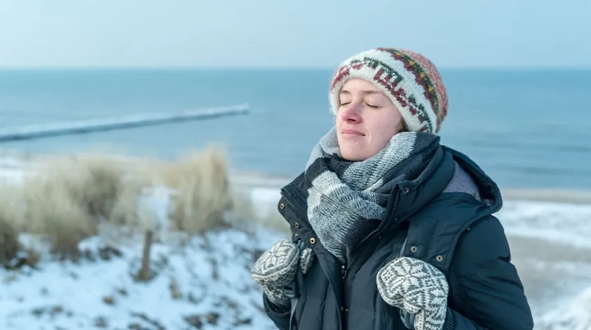 Frau, die an der Ostsee steht und während der Rauhnächte durchatmet. © AdobeStock, EmDali