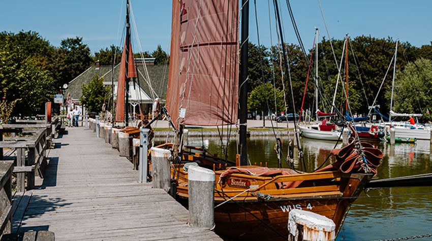 Althagener Hafen in Ahrenshoop mit Booten, Stegen und bunten Boddenhäusern am ruhigen Wasser.