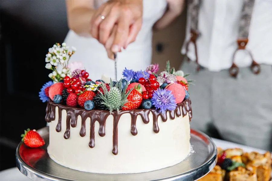 Brautpaar schneidet gemeinsam eine festlich dekorierte Hochzeitstorte im THE GRAND Ahrenshoop.