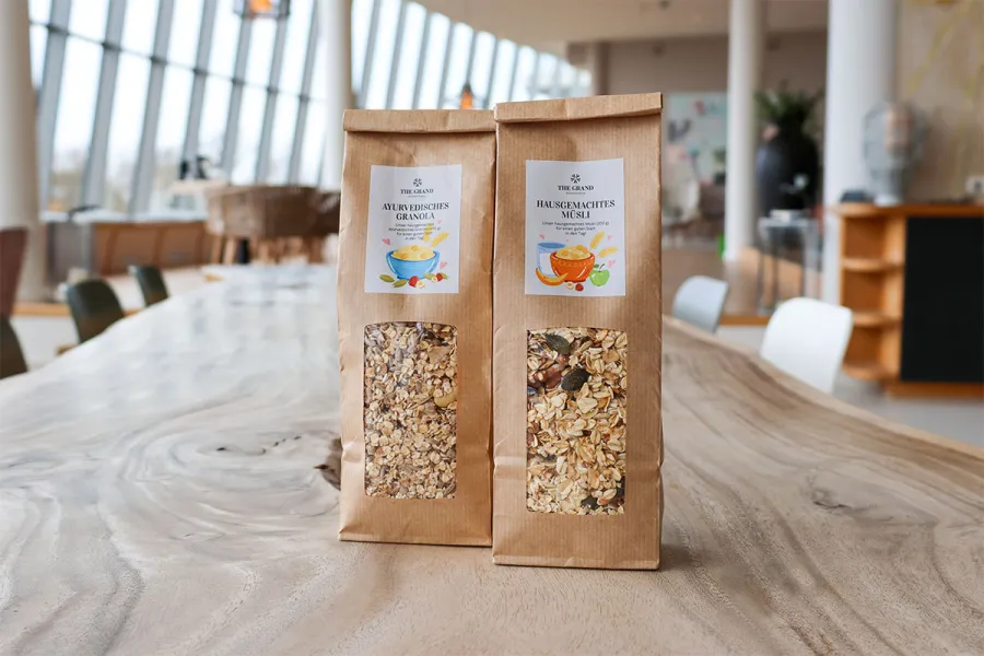 Zwei Sorten hausgemachtes Müsli in umweltfreundlichen Papiertüten mit bunten Etiketten.