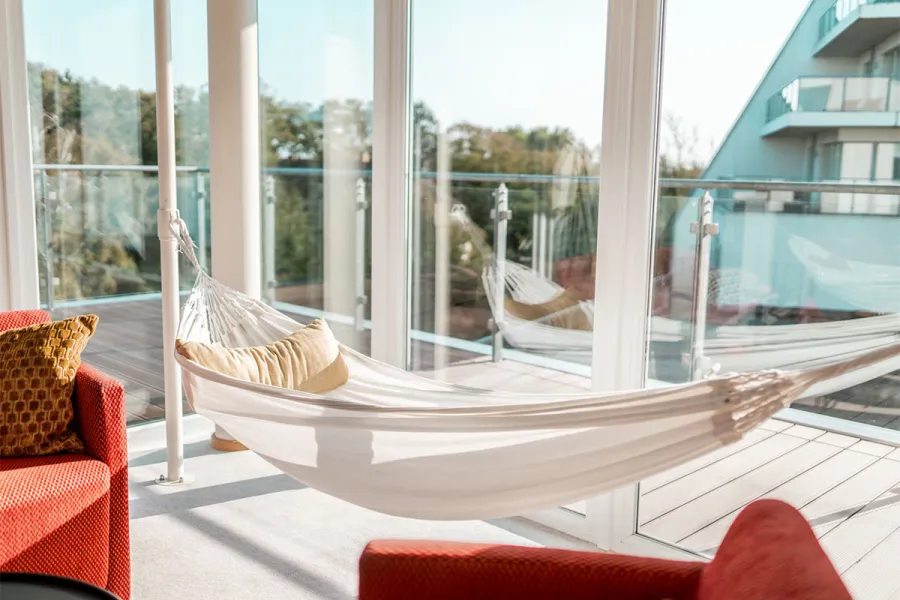 Hängematte im Zimmer vom THE GRAND Ahrenshoop mit Blick nach draußen.