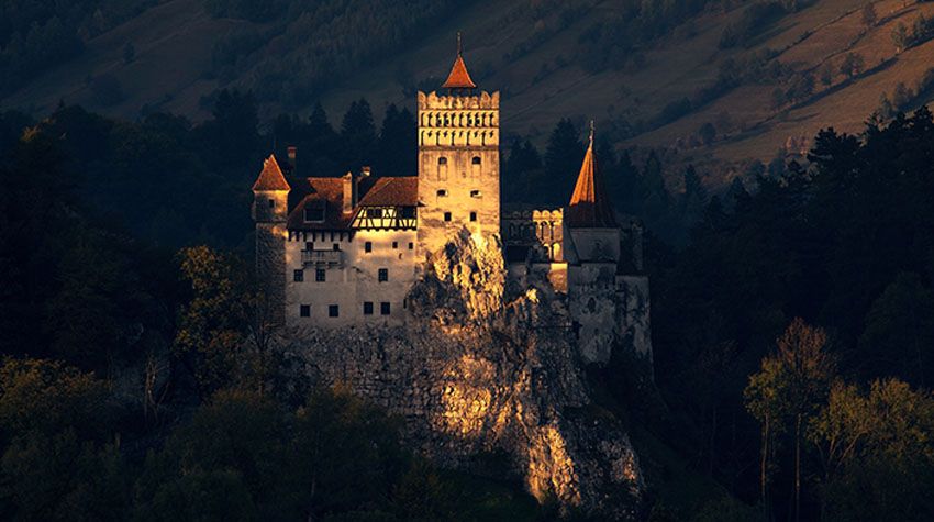 Das berühmte Schloss Dracula in Transsilvanien, geheimnisvoll beleuchtet vor dunklen Wäldern und Bergen.