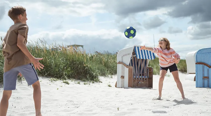 Zwei Kinder spielen Beachvolleyball am Ostseestrand