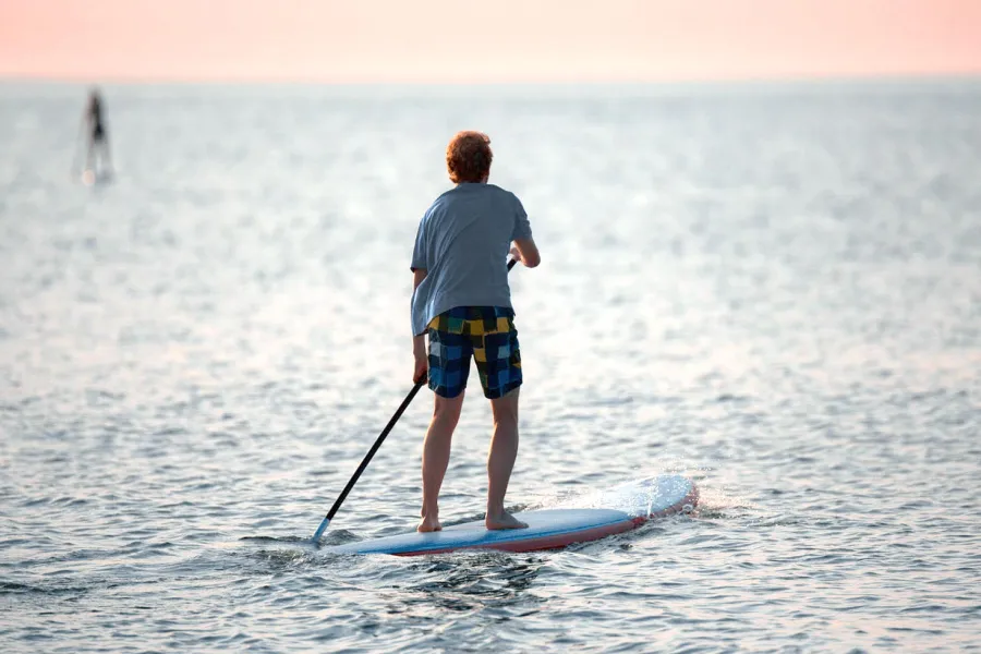 Person beim Stand-up-Paddling auf der Ostsee im Abendlicht.