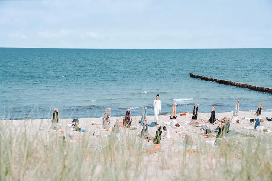 Yoga am Strand von Ahrenshoop mit Gruppe vor der Ostsee.