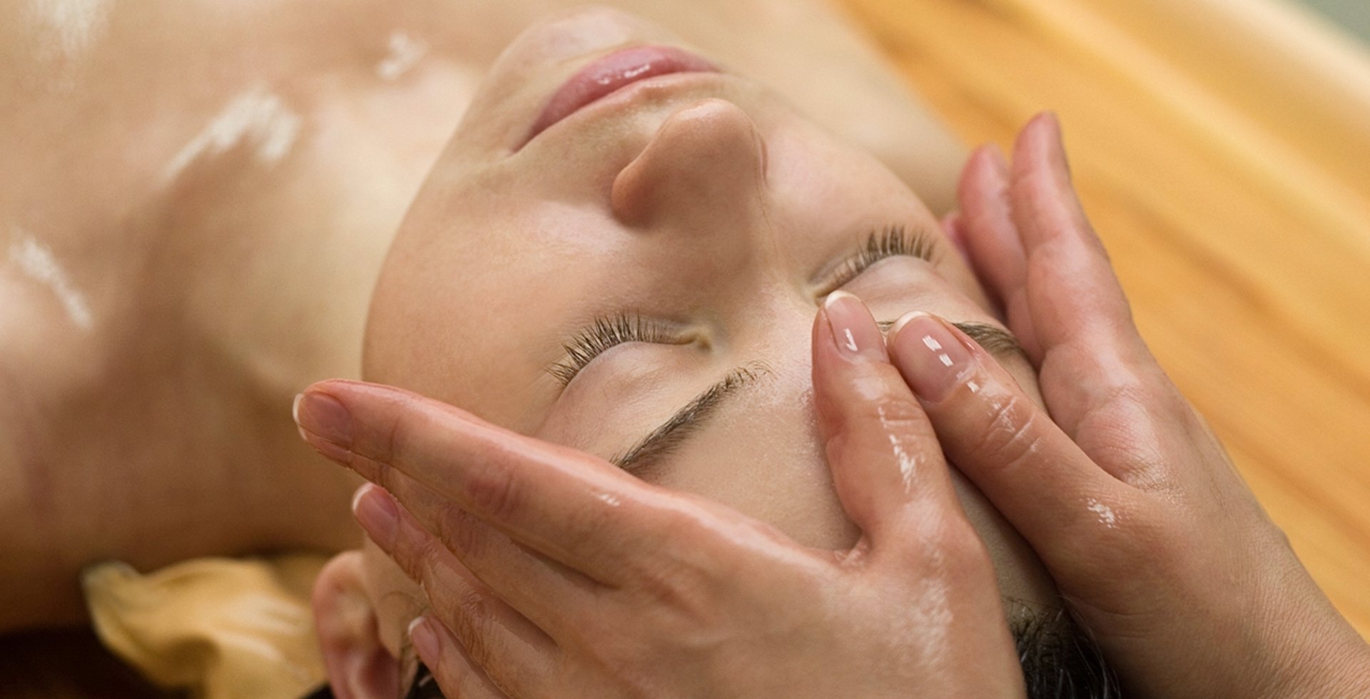 Eine Person erhält eine entspannende ayurvedische Gesichtsmassage mit Öl, durchgeführt von einem Therapeuten in ruhiger Wellness-Atmosphäre.