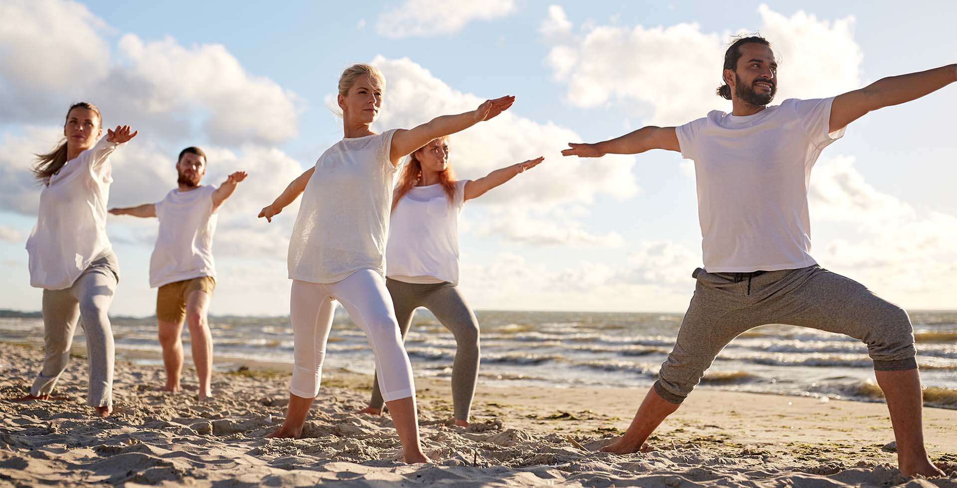 Menschen praktizieren Yoga am Strand bei Sonnenlicht während des Weltyogatags nahe THE GRAND Ahrenshoop