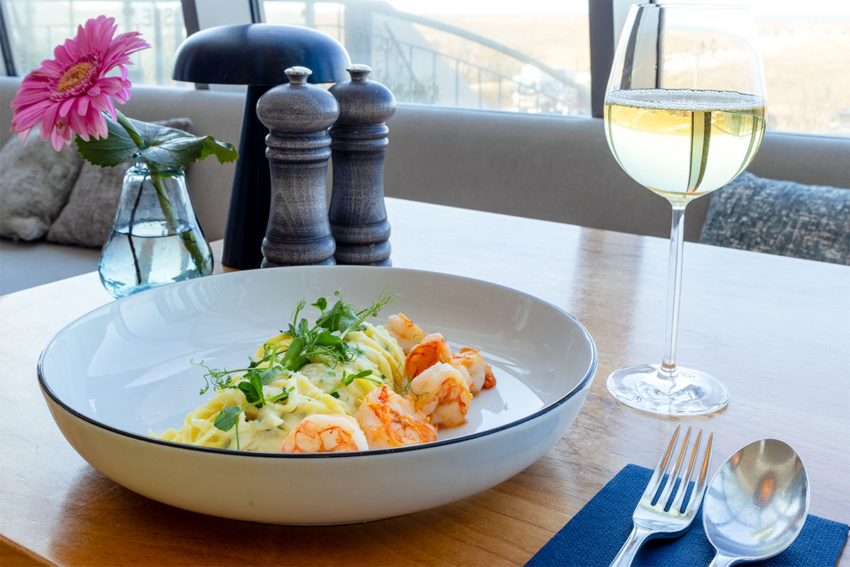 Garnelen mit Pasta und Weißwein auf einem Tisch im Restaurant SEASIDE im THE GRAND Ahrenshoop