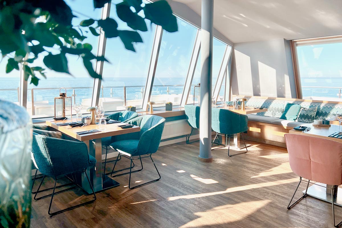 Restaurantbereich im THE GRAND Ahrenshoop mit großen Fenstern und direktem Blick auf die Ostsee.