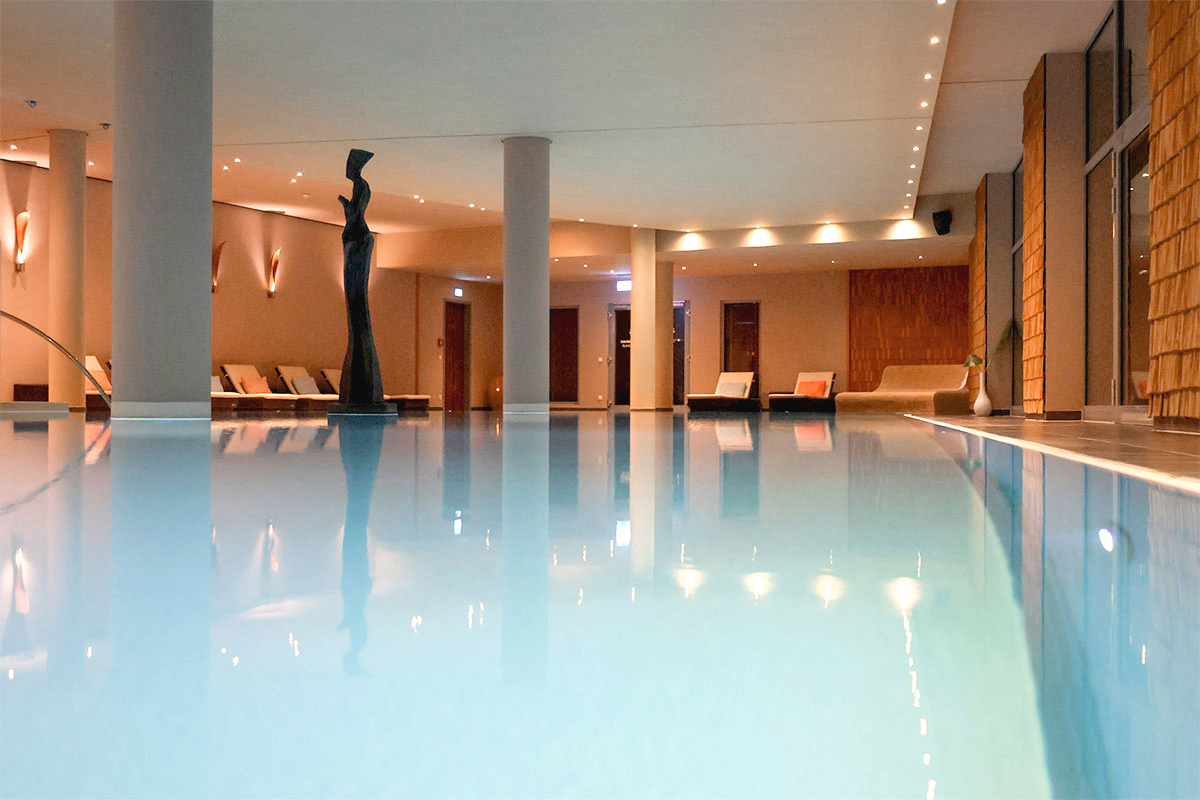 Innenpool im Spa des THE GRAND Ahrenshoop mit Liegen und warmem Licht.