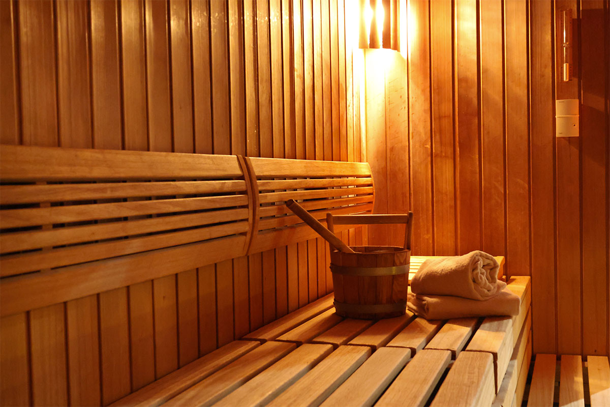 Sauna im Spa des THE GRAND Ahrenshoop mit Holzbank, Aufgusskübel und Handtüchern.